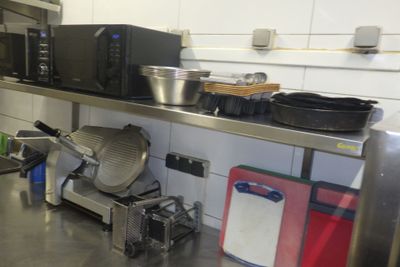 plan de travail en acier inoxydable dans une cuisine professionnelle équipée de fours à micro-ondes, de casseroles et de poêles