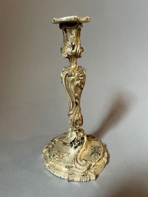 a gold candle holder on a table with a shadow on the floor