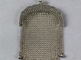 un gros plan d'un sac à main à chaîne argentée posé sur une surface blanche
