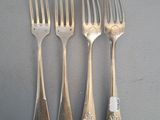 four forks and a knife are lined up on a table
