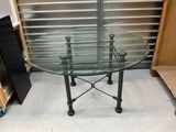 une table en verre avec des pieds en métal et un plateau en verre
