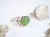three rings with a green stone on top of them on a white surface