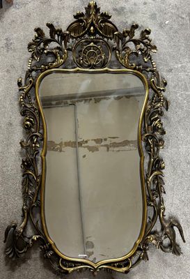 an antique mirror with a gold frame sitting on the floor