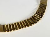 a gold bracelet that is on a white surface