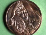 une image représentant une médaille de bronze sur laquelle figure une femme tenant un bébé dans ses bras