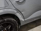 a cat sitting on the side of a car with it ' s paw on the wheel