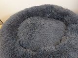 a gray dog bed on a wooden floor next to a wall
