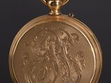 an antique gold pocket watch on a black surface with a black background