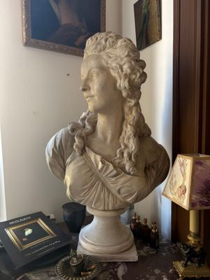 a bust of a woman sitting on a table next to a lamp