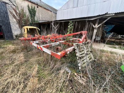 un tracteur qui est garé dans l'herbe près d'un bâtiment