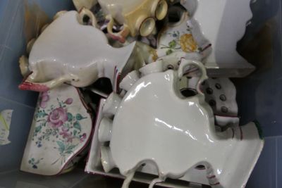 une boîte remplie de tasses à thé et de soucoupes, ainsi qu'un ours en peluche