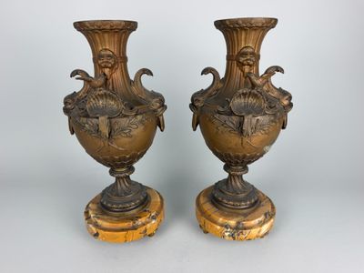 paire de vases anciens en bronze reposant sur des socles en bois, sur fond blanc