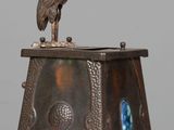 a metal clock with a bird on top of it