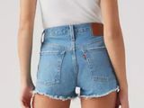 the back view of a woman in a white tank top and blue denim shorts