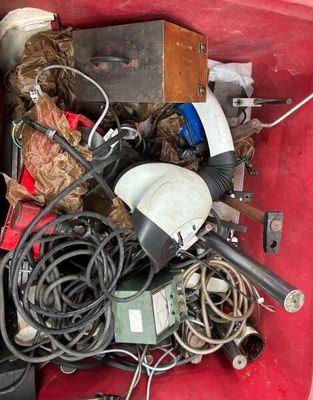 un tas de bric-à-brac dans une boîte rouge posée par terre