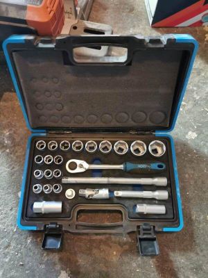 un jeu d'outils rangé dans une boîte à outils posée par terre
