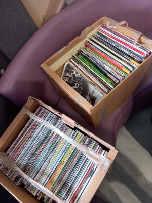 two boxes full of cds sitting on a purple chair
