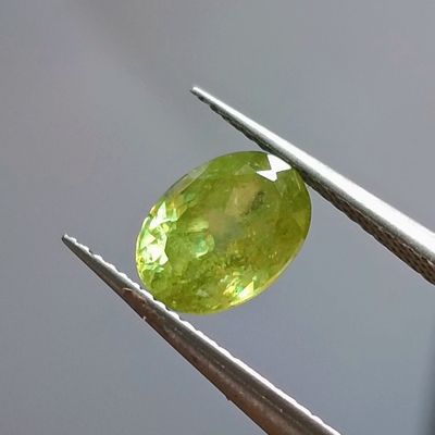 une pierre précieuse verte maintenue par une paire de pinces