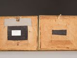 an old wooden box with two pictures inside of it on a table