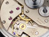 a close up of a silver watch with gears on it