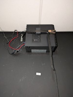 une petite boîte noire à laquelle sont reliés des fils, dans une pièce