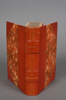 an old book with a red cover sitting on top of a table