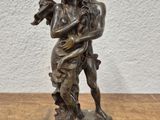 statue en bronze représentant une femme tenant un enfant, posée sur une table en bois