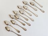 six silver spoons are arranged in a row on a white surface