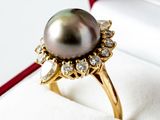 a black pearl and diamond ring in a red box