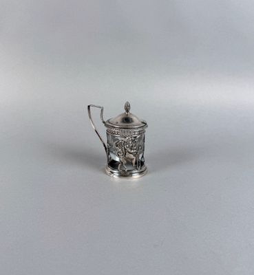une théière ancienne en argent, dotée d'une anse, posée sur une surface blanche