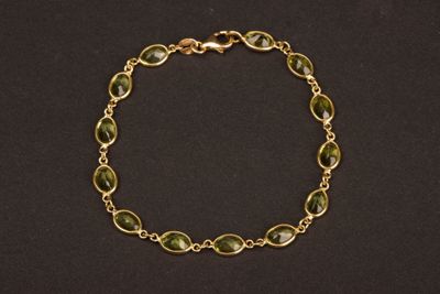 un bracelet en or orné de perles de verre vertes sur fond noir