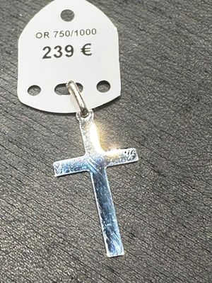une croix en argent à laquelle est attachée une étiquette
