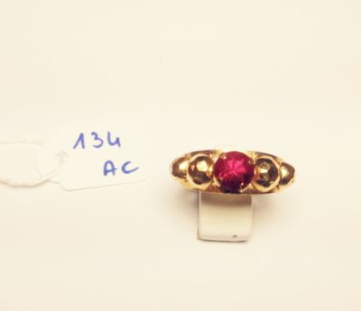 a close up of a gold ring with a red stone on it