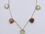 a gold necklace with green and brown stones on it