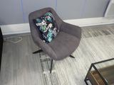 un fauteuil gris avec un coussin posé dessus, dans un salon
