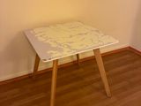 une petite table blanche aux pieds en bois dans une pièce