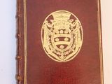 an old brown leather book with a gold seal on it