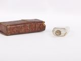 a small book and a small glass object on a white surface