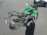 a green motorcycle parked in a parking lot next to a car