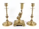 three brass candlesticks with a bird on top of them