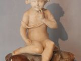 a small statue of a child sitting on a rock
