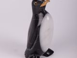 une petite figurine de pingouin en noir et blanc posée sur une surface blanche