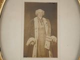an old picture of a man wearing a robe and holding a cane