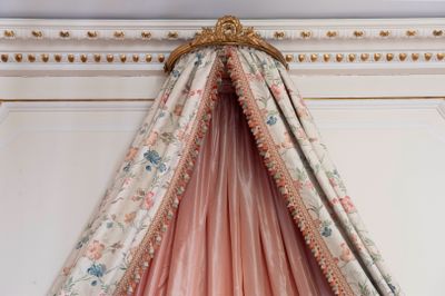 a bed with a pink canopy hanging from it ' s ceiling