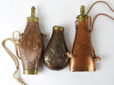 three antique brass vases are lined up on a white surface