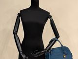 female mannequin holding a blue purse and a blue purse
