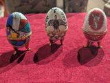 trois œufs décorés posés sur une nappe rouge