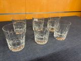 four glasses are lined up on a table in front of a wooden wall