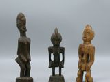 three wooden figurines of different shapes and sizes on a white surface