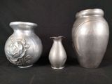 three silver vases sitting next to each other on a black background